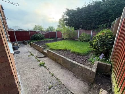 The same garden before the work: cracked concrete, a low concrete block retaining wall and patchy grass.