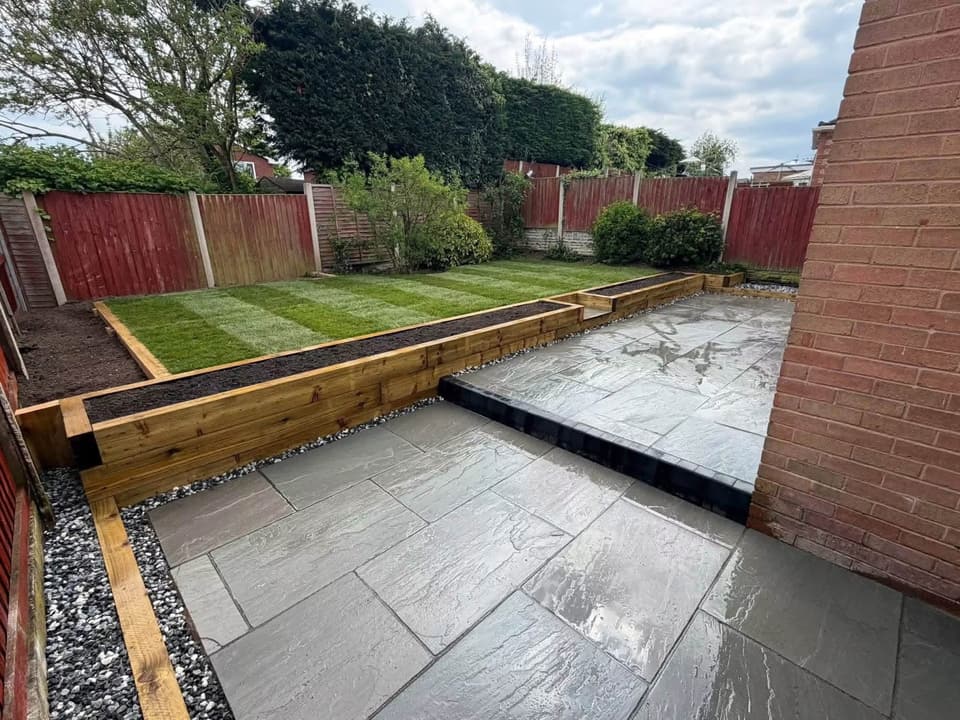 A finished garden: riven porcelain paving, a timber sleeper retaining edge and freshly laid striped turf.